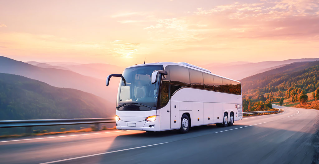 Modern tourism bus with large windows traveling along a cypress-lined road through rolling Tuscan hills