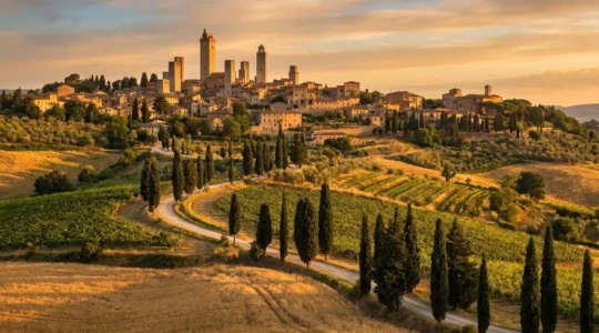 Panoramic view of San Gimignano's medieval towers rising from rolling Tuscan hills with cypress-lined roads winding through vineyard landscapes in golden afternoon light